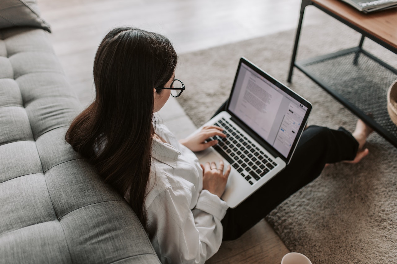 kobieta siedząca na podłodze z laptopem wykonująca przelew na mikrorachunek podatkowy