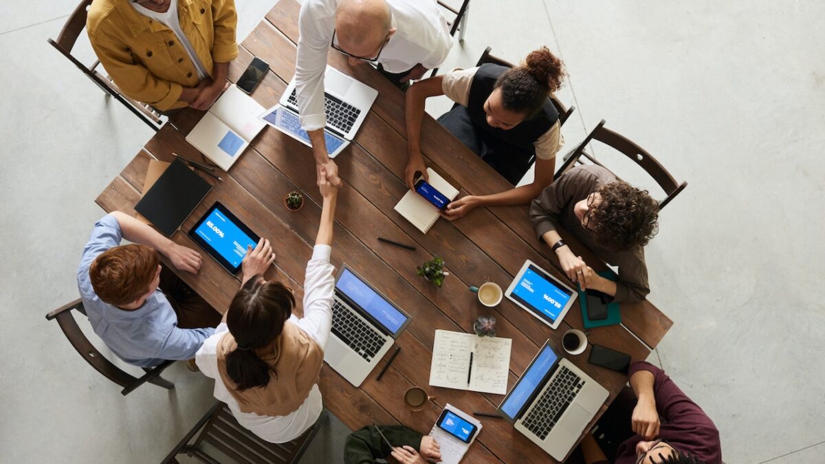Przedsiębiorcy z laptopami siedzący przy stole i omawiający formy opodatkowania działalności gospodarczej